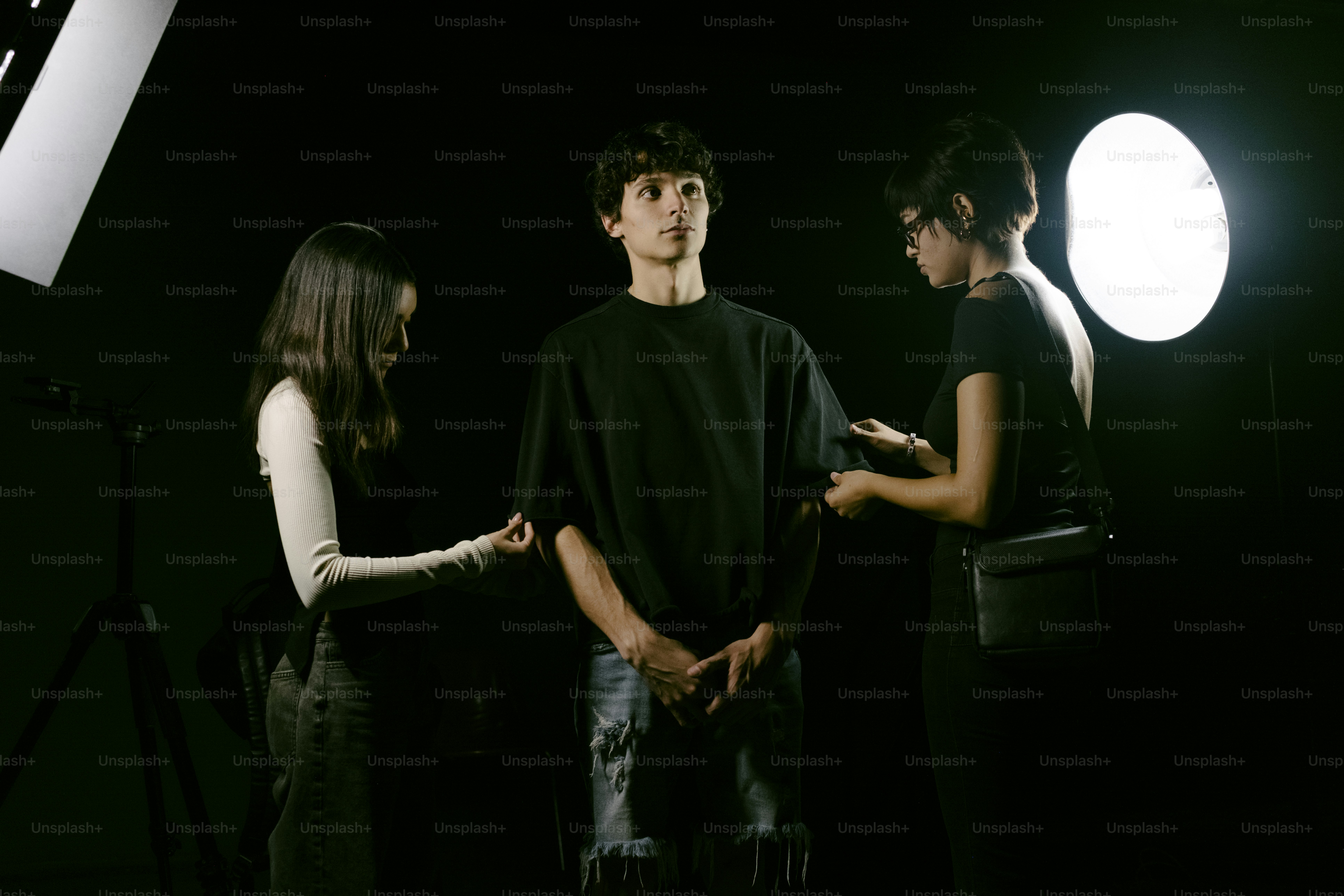 Two people adjust clothing on a young man.